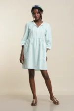 Front view of women's empire waist dress in mint green linen with V-neck, long sleeves, and knee length on model