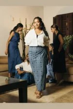 Woman modeling blue patterned wrap skirt with white shirt, full-length view showing elegant drape of cotton blend fabric