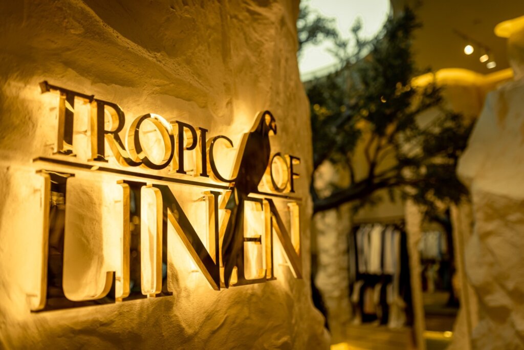 Tropic of Linen sign on the sandstone wall of the City of Dreams store
